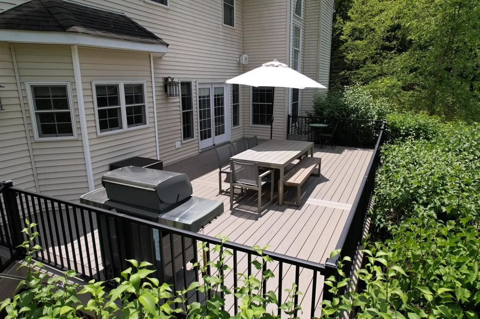 Finished deck with black metal railing, dining area, and grill station