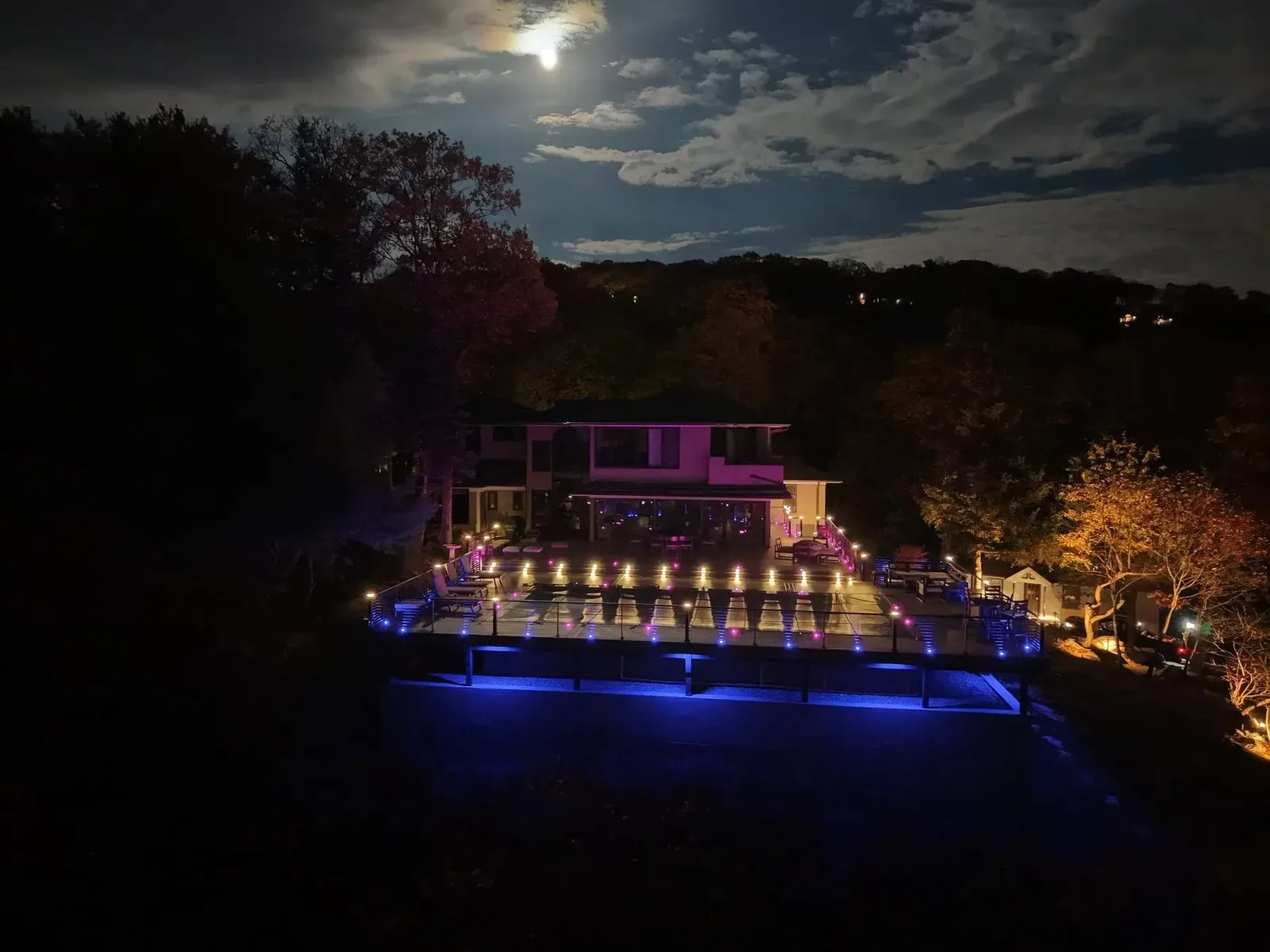 Outdoor living and a lit pool under a full moon on an autumn night
