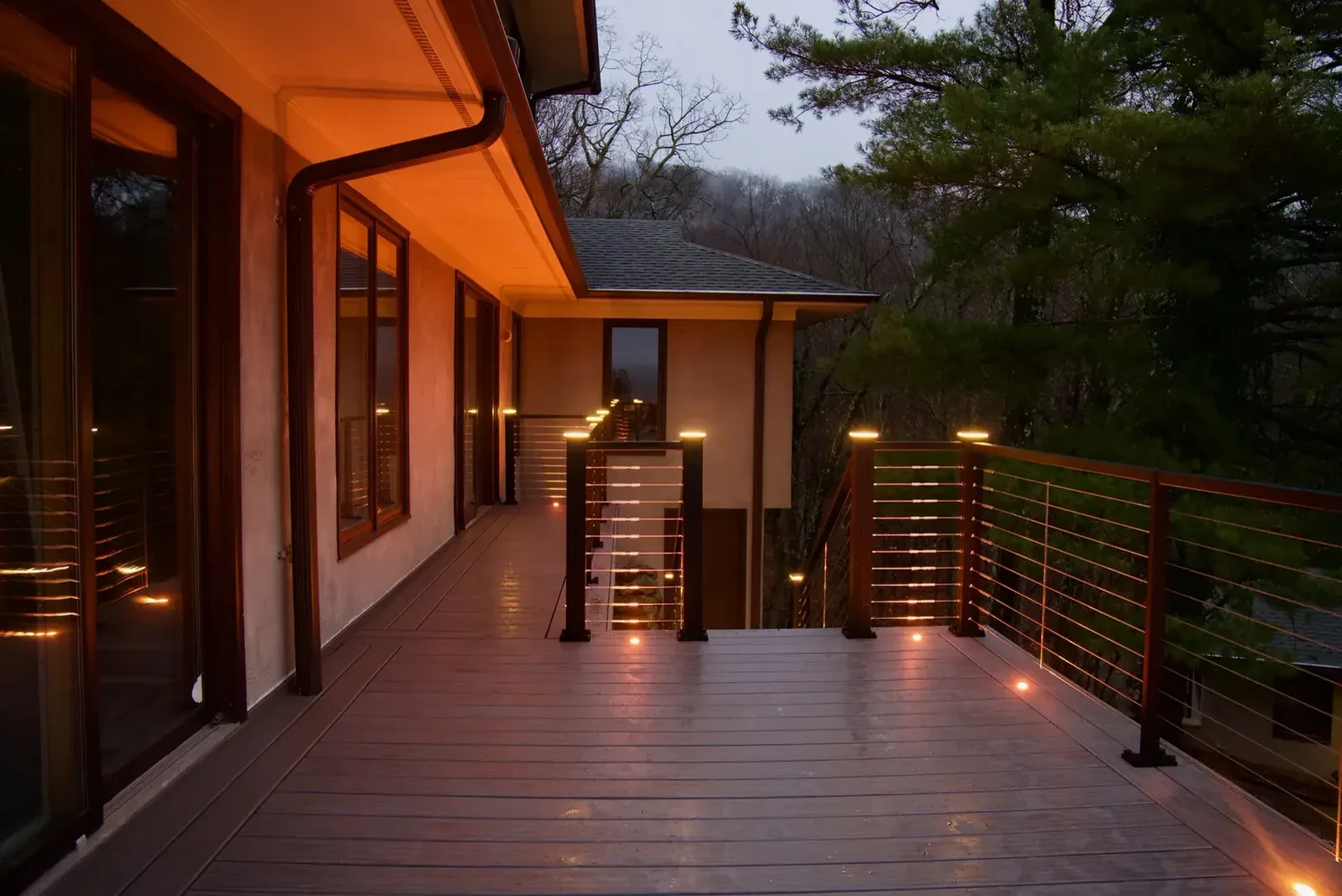 Covered deck with a fire feature and post lighting at dusk