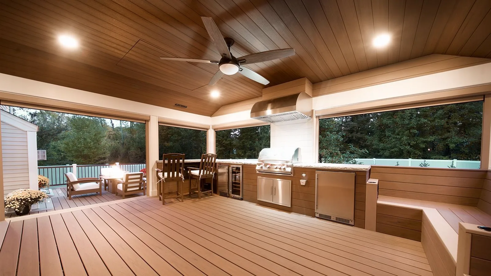 Covered porch outdoor living room with a built-in kitchen and ceiling fan