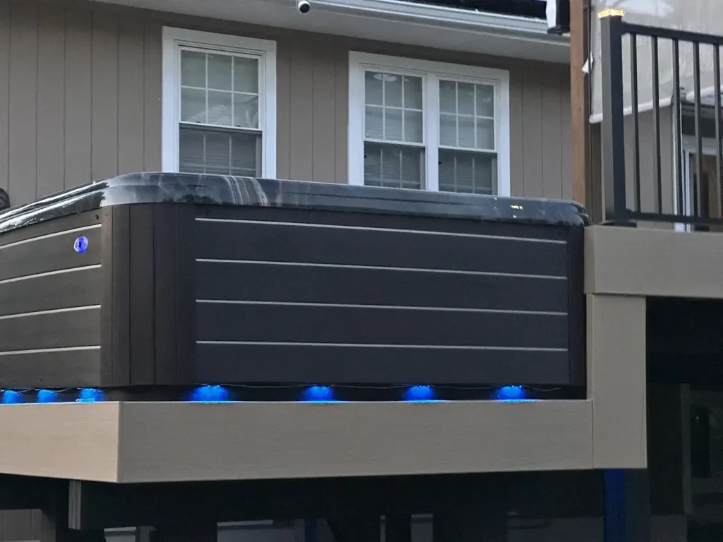 Deck with hot tub under blue LED lighting at dusk