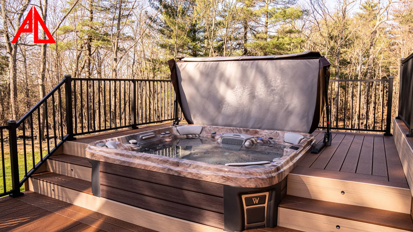 Spa integrated into a Trex Select deck at golden hour, black Trex Signature railing and woods beyond