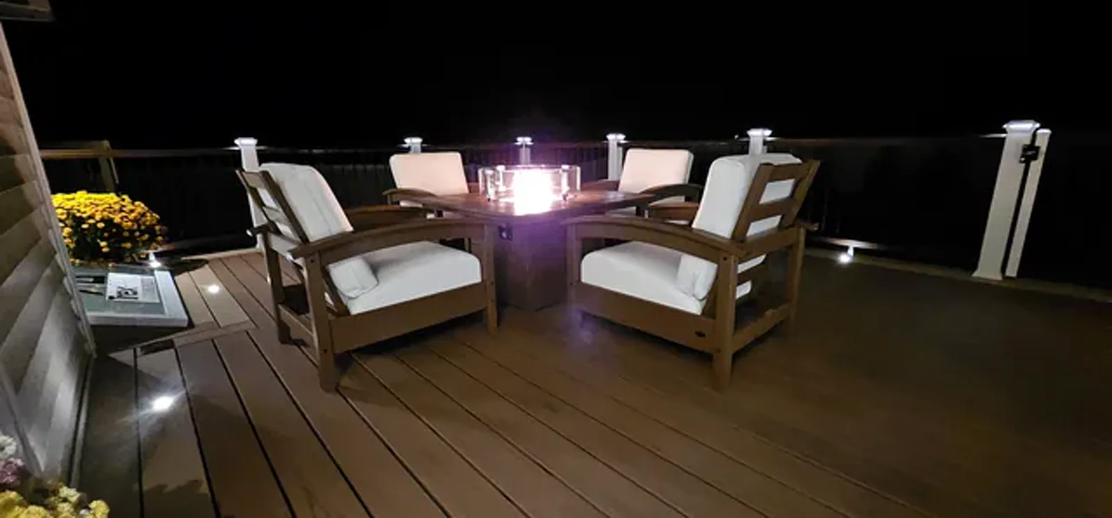 Fire table and chairs lit on a deck at night