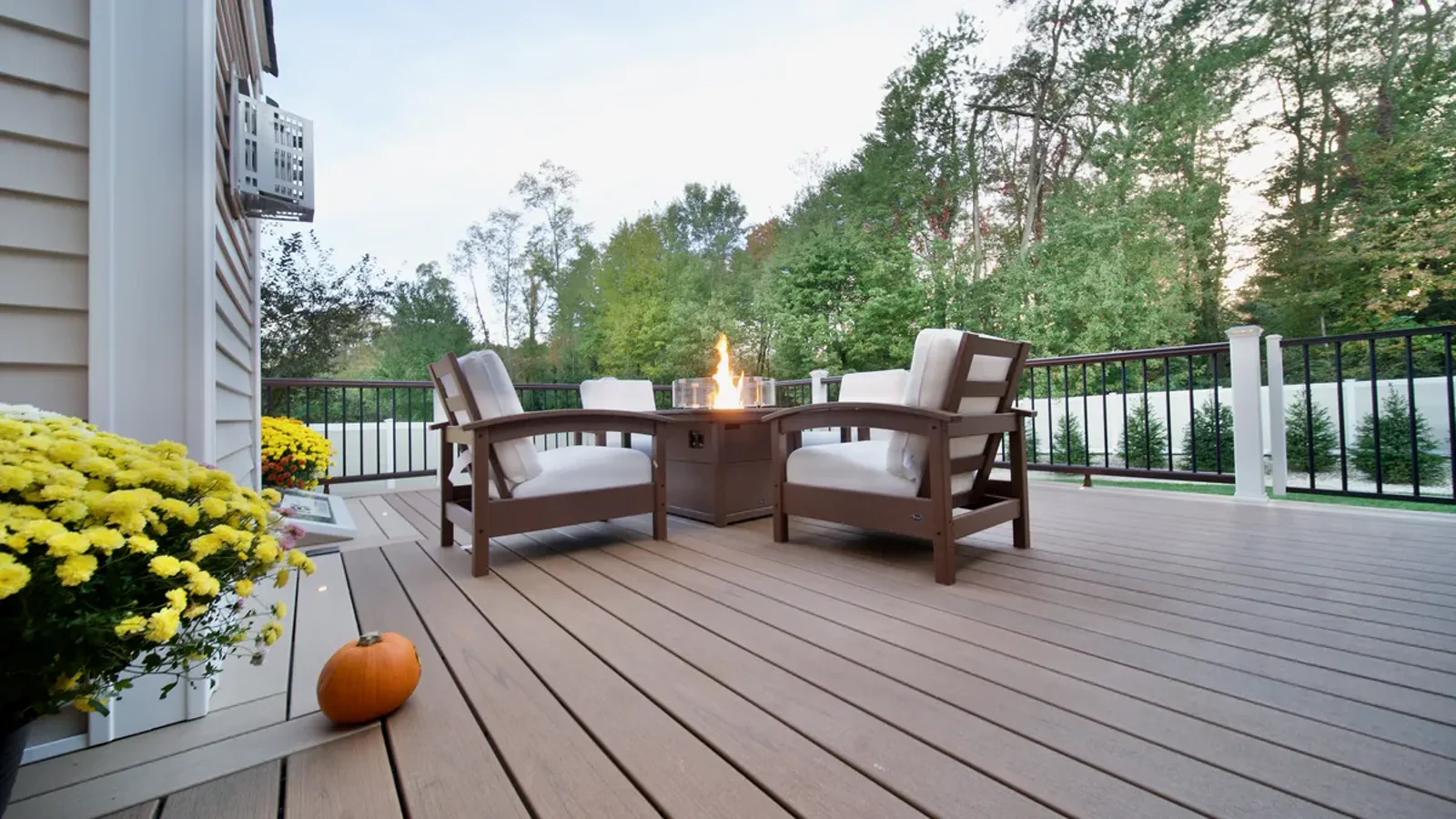 Finished deck with a fire table, cable railing, and autumn planting
