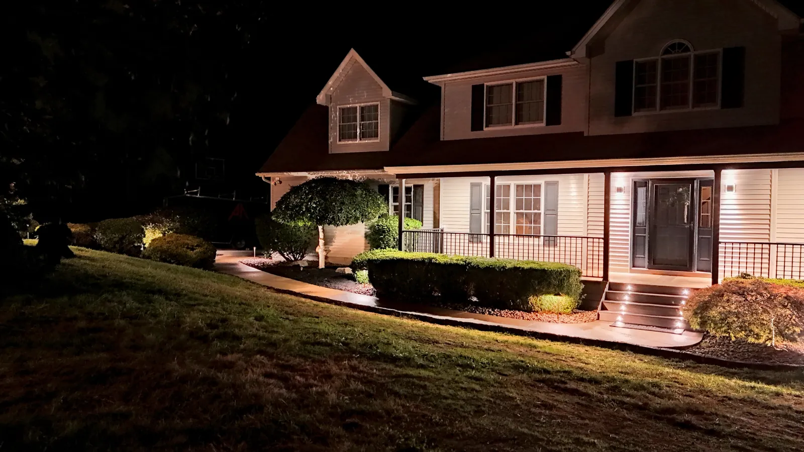 Front walkway, porch and plantings lit at night by low-voltage landscape lighting