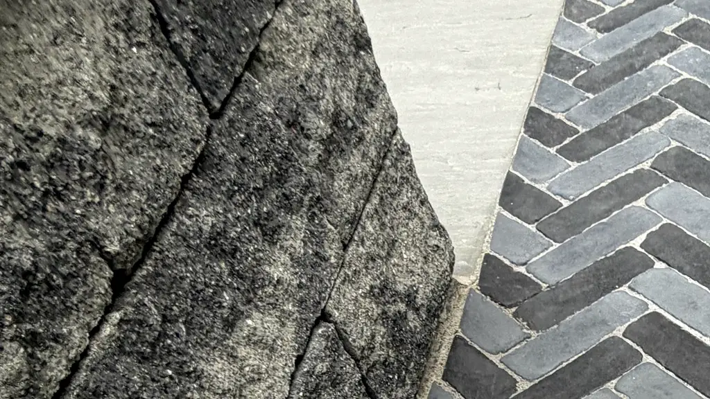 Close-up detail of natural stone edging beside a dark gray herringbone paver patio