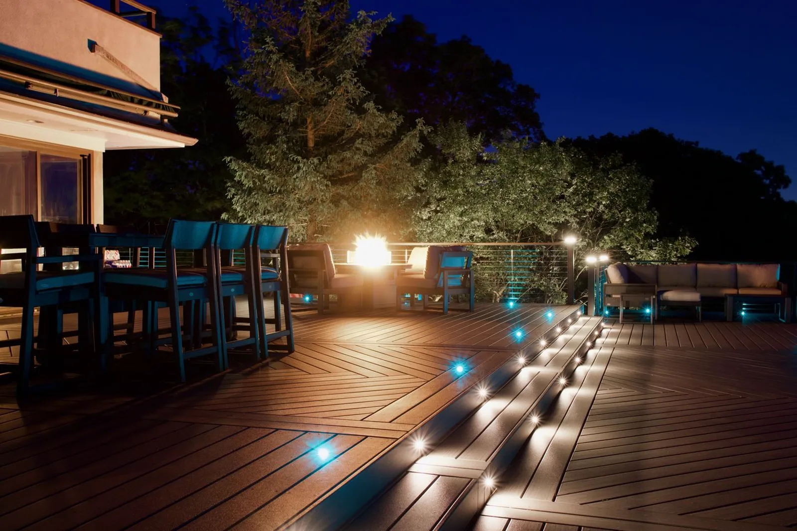 Zoned deck lighting running at night, riser lights on the steps and in-deck fixtures at the edges