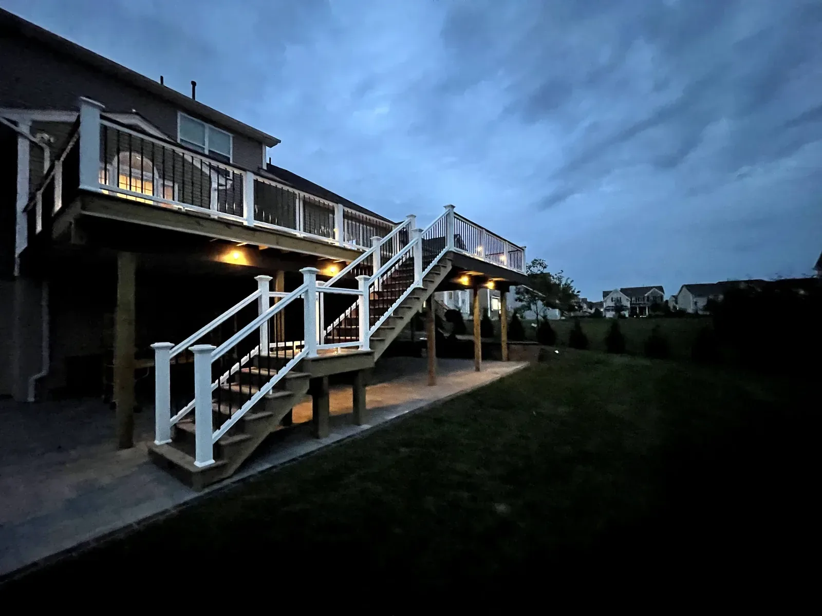 Straight fascia line and stair wrap on an elevated composite deck at dusk