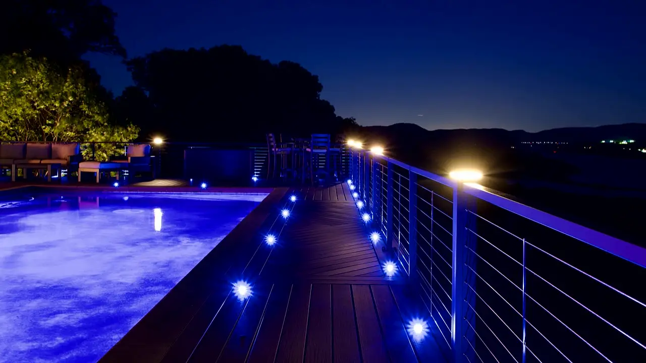 Black aluminum railing and blue pool deck lighting at night