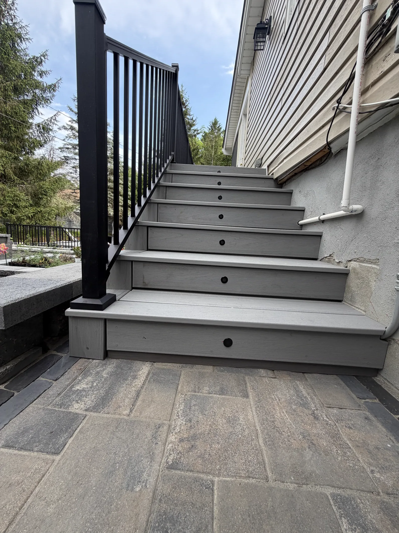 Finished stair riser lighting glowing under black aluminum railing at night