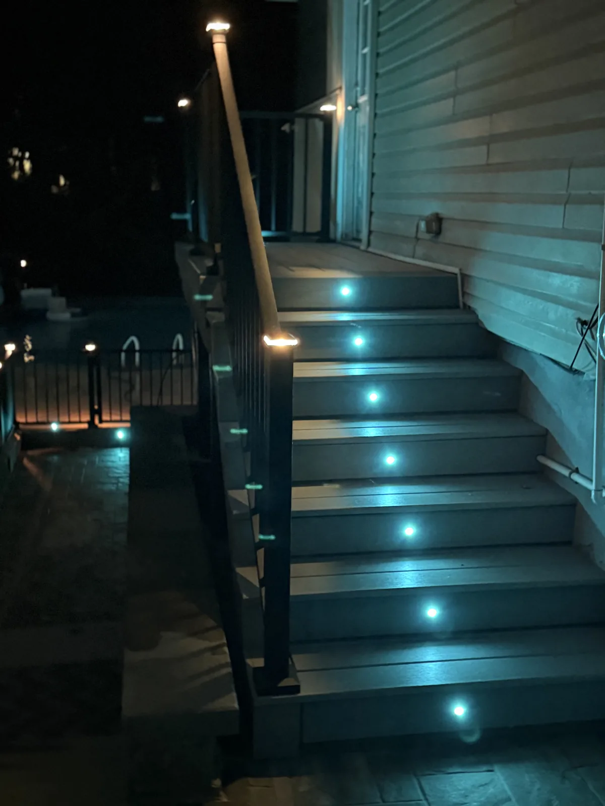 Stair riser lights on a black-railing deck at night