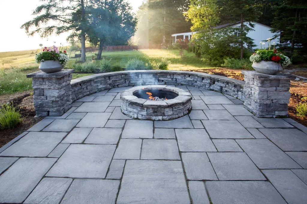 Golden-hour bluestone patio with stone seat wall and fire pit
