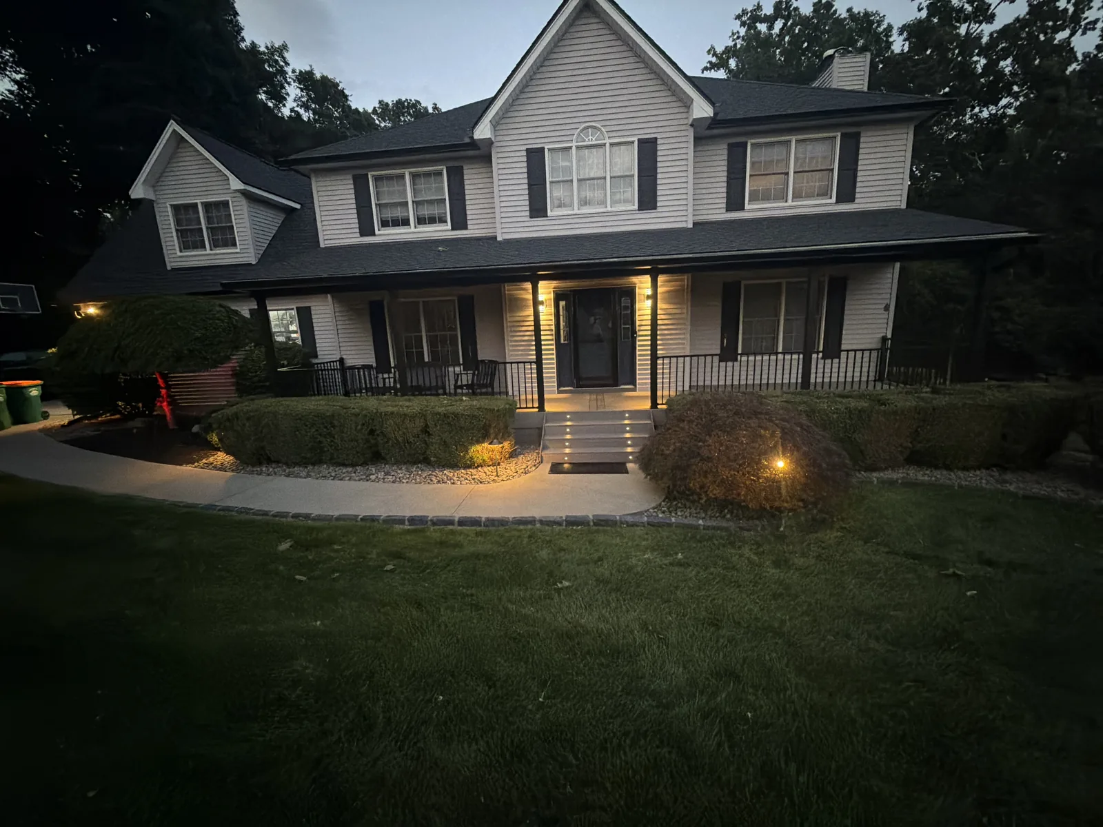 Front of the home at dusk — porch, walkway with cobblestone accent borders, and landscape lighting