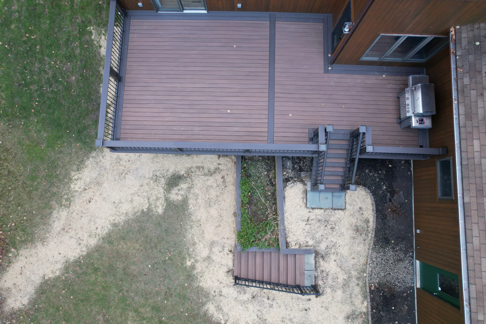 Overhead view of a TimberTech deck with a bordered field, two stair runs, and a grill station