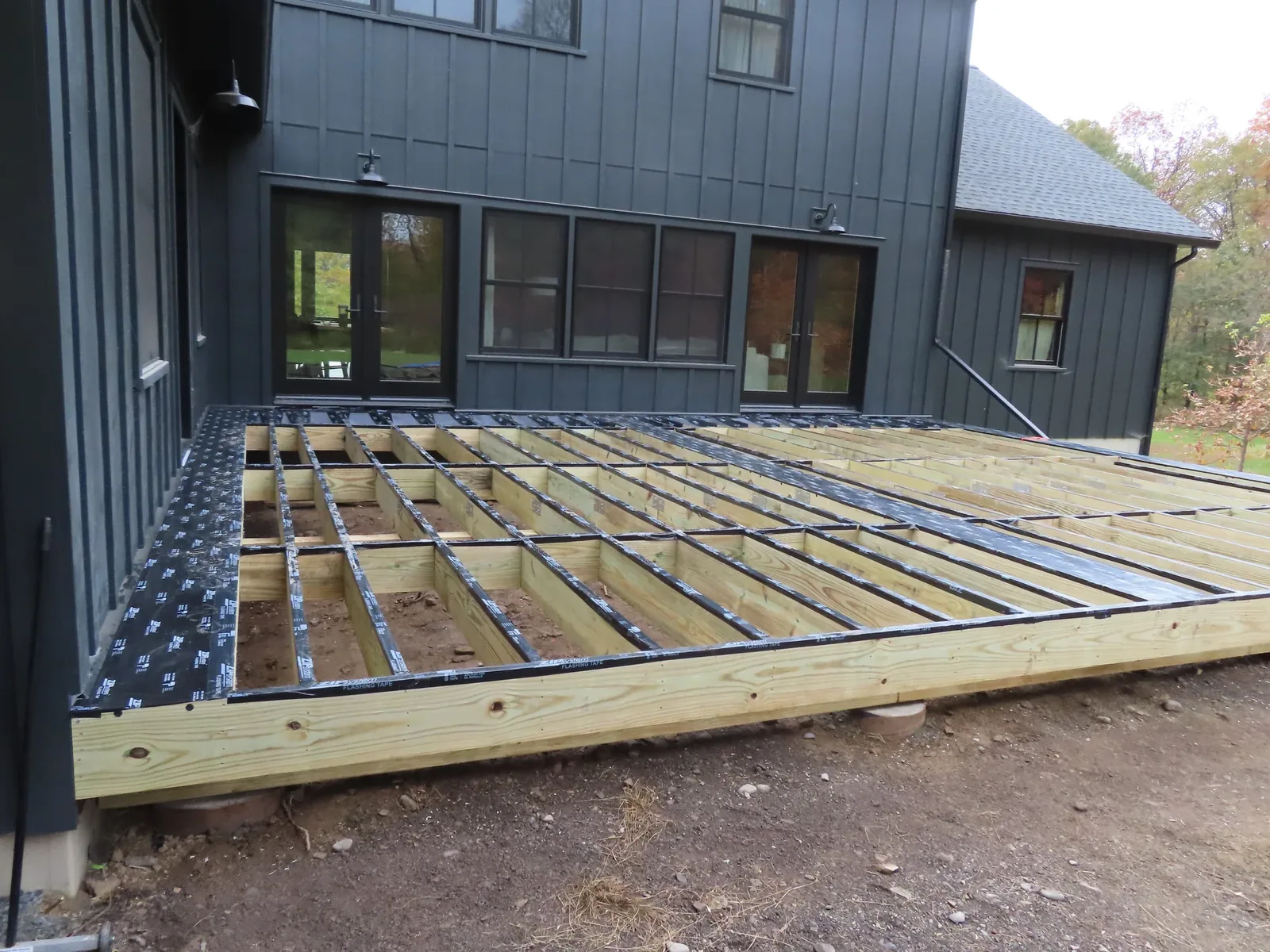 Composite deck with a pergola frame and paver patio
