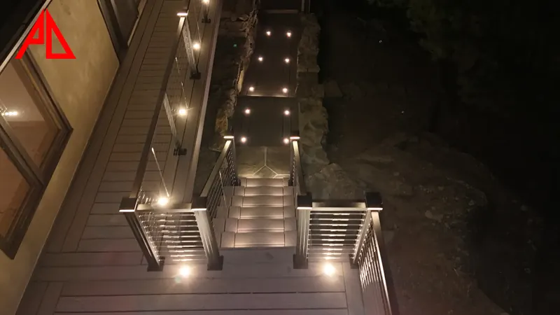 Warm white riser lights on deck stair treads and post-cap lights glowing on the railing at night
