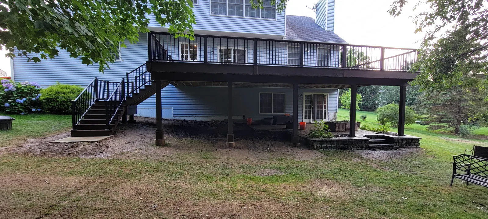 Elevated composite deck with a side staircase over a landscaped yard in the Hudson Valley