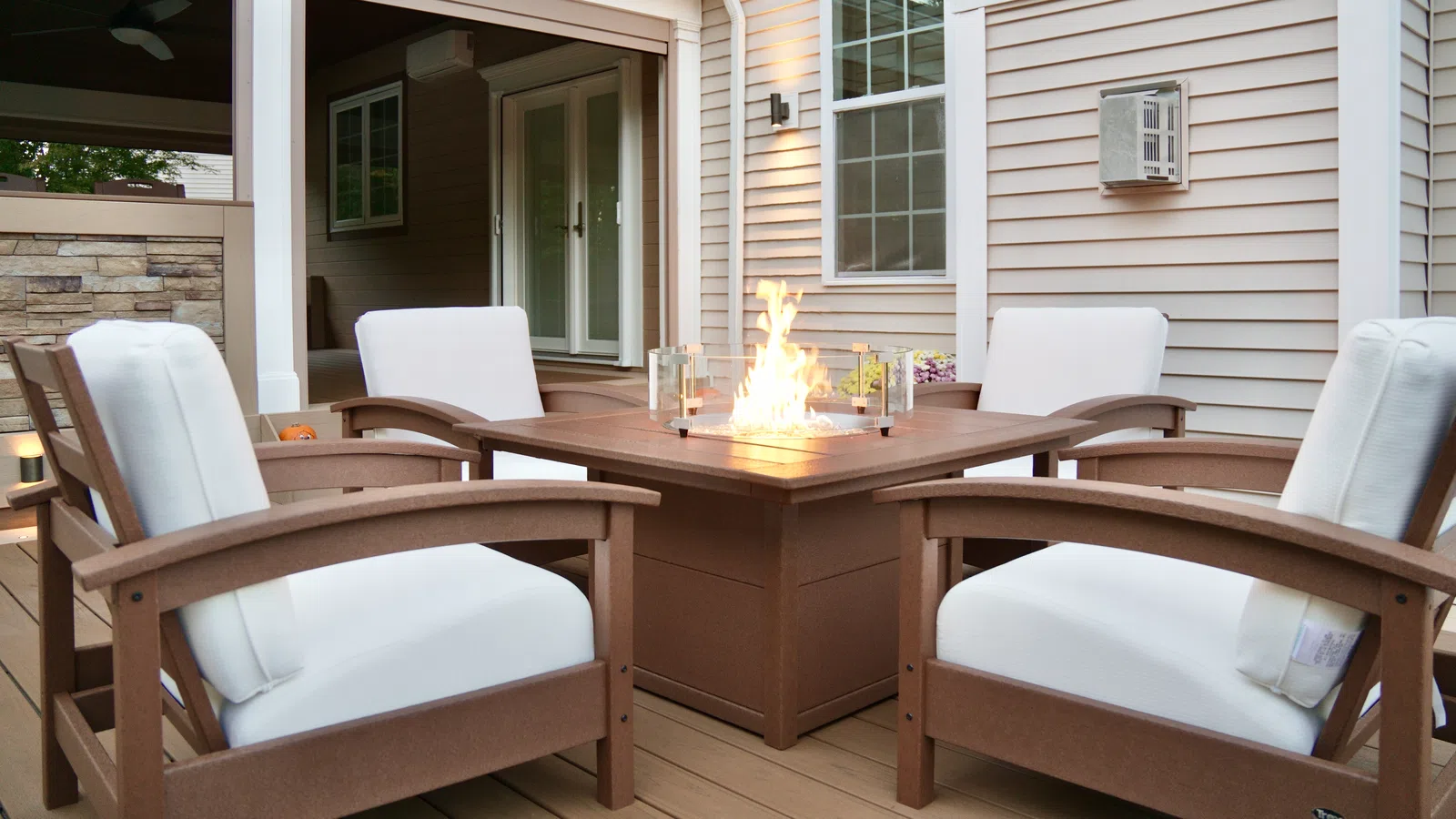 Fire table lounge seating on a composite deck at dusk