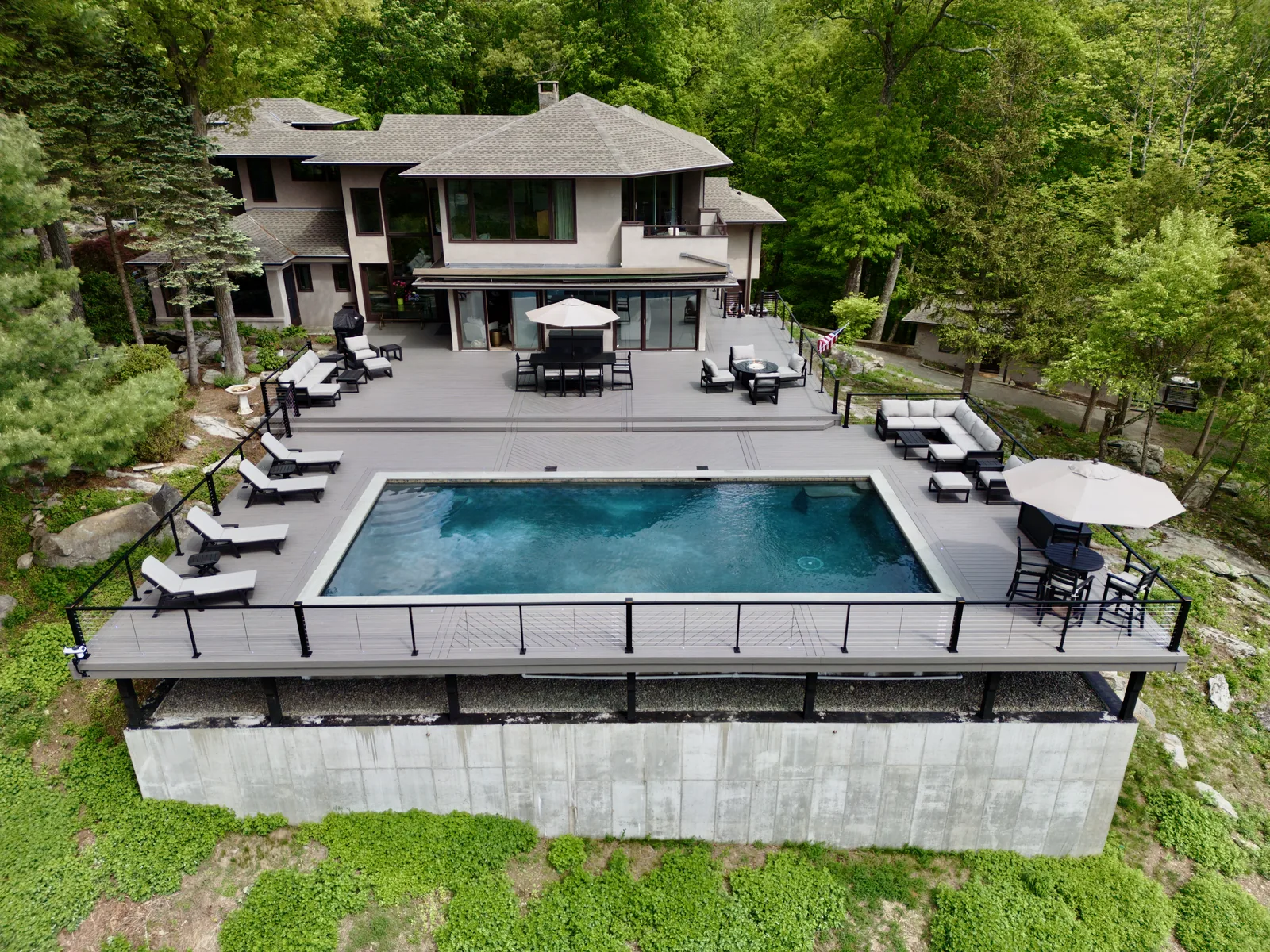 Elevated pool deck with Signature cable railing and lounge zones in Garrison, NY