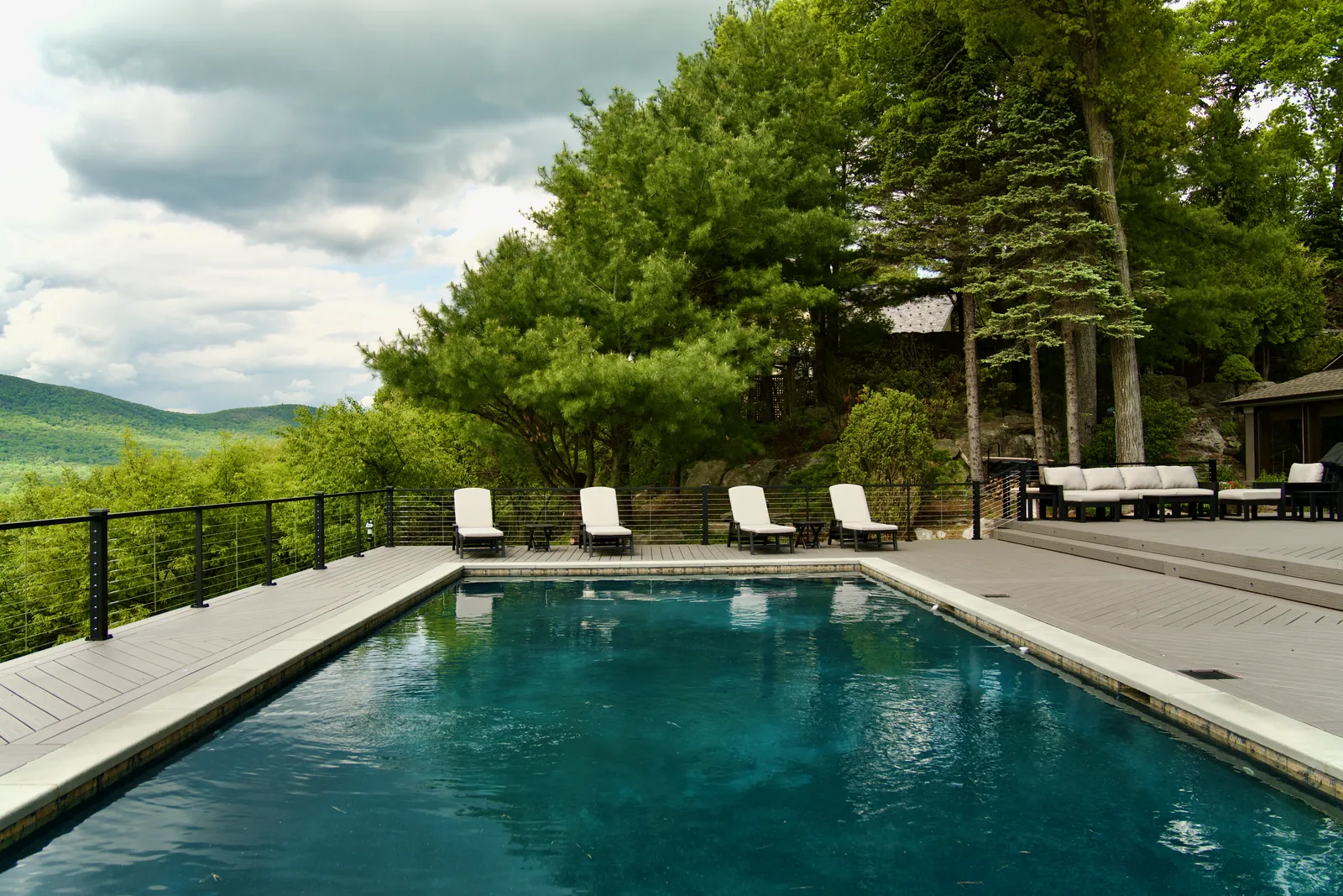 Pool with mountain backdrop and tall pines in Garrison, NY