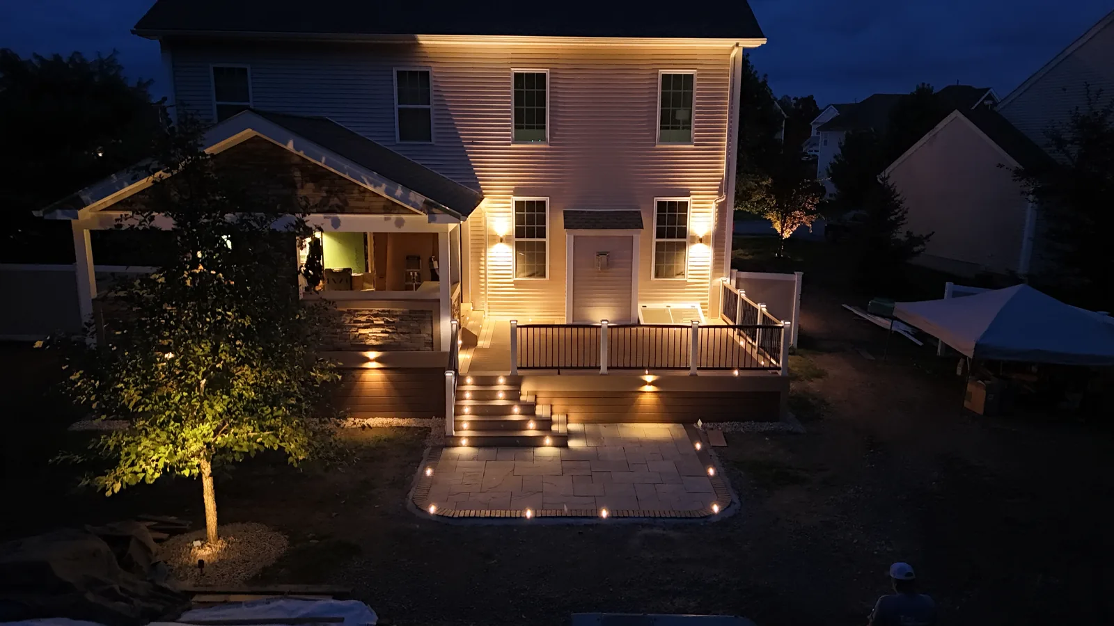 Twilight rear deck and covered porch glowing with landscape lighting in the Hudson Valley, NY
