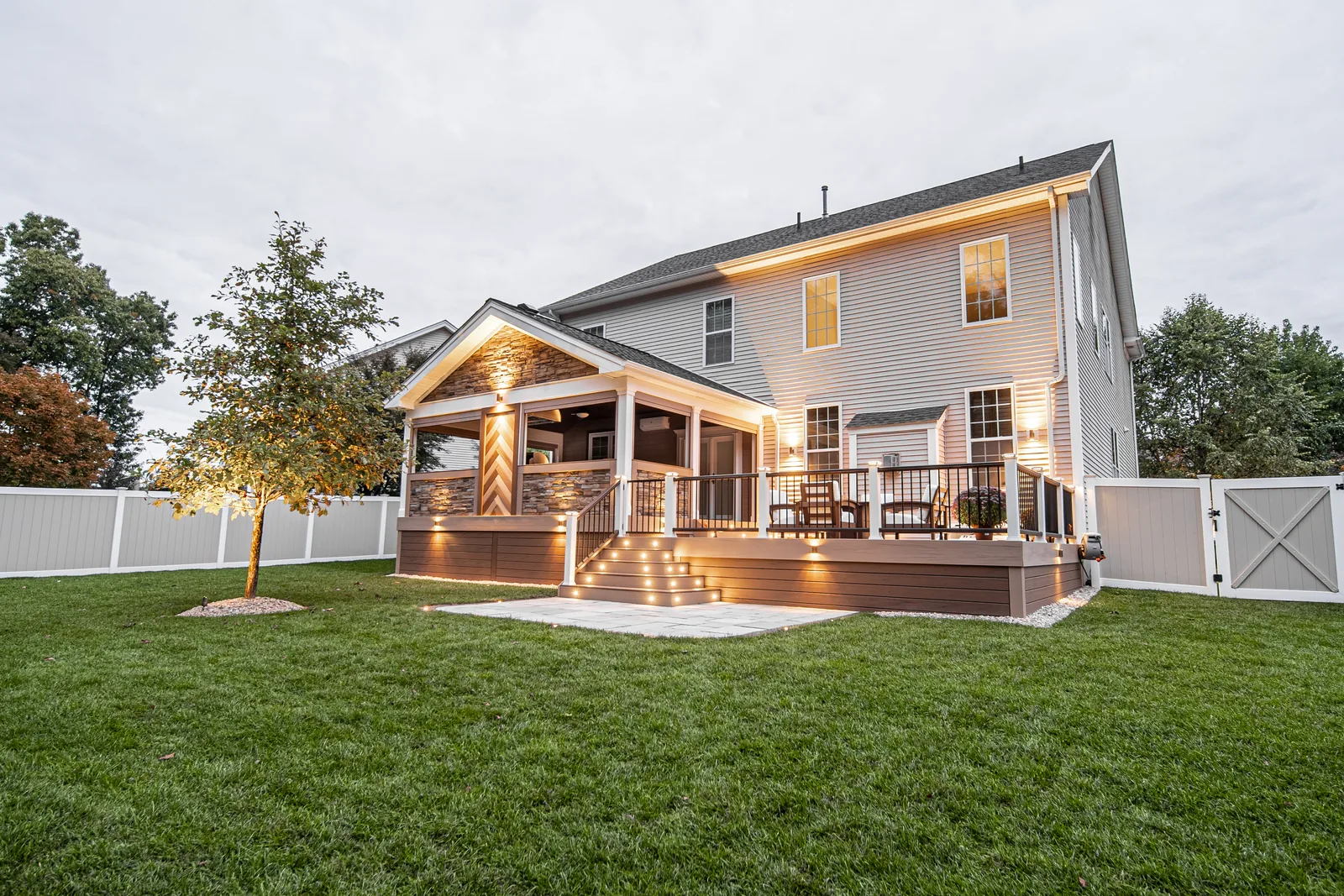 Twilight covered porch with stone columns and warm deck lighting in the Hudson Valley, NY
