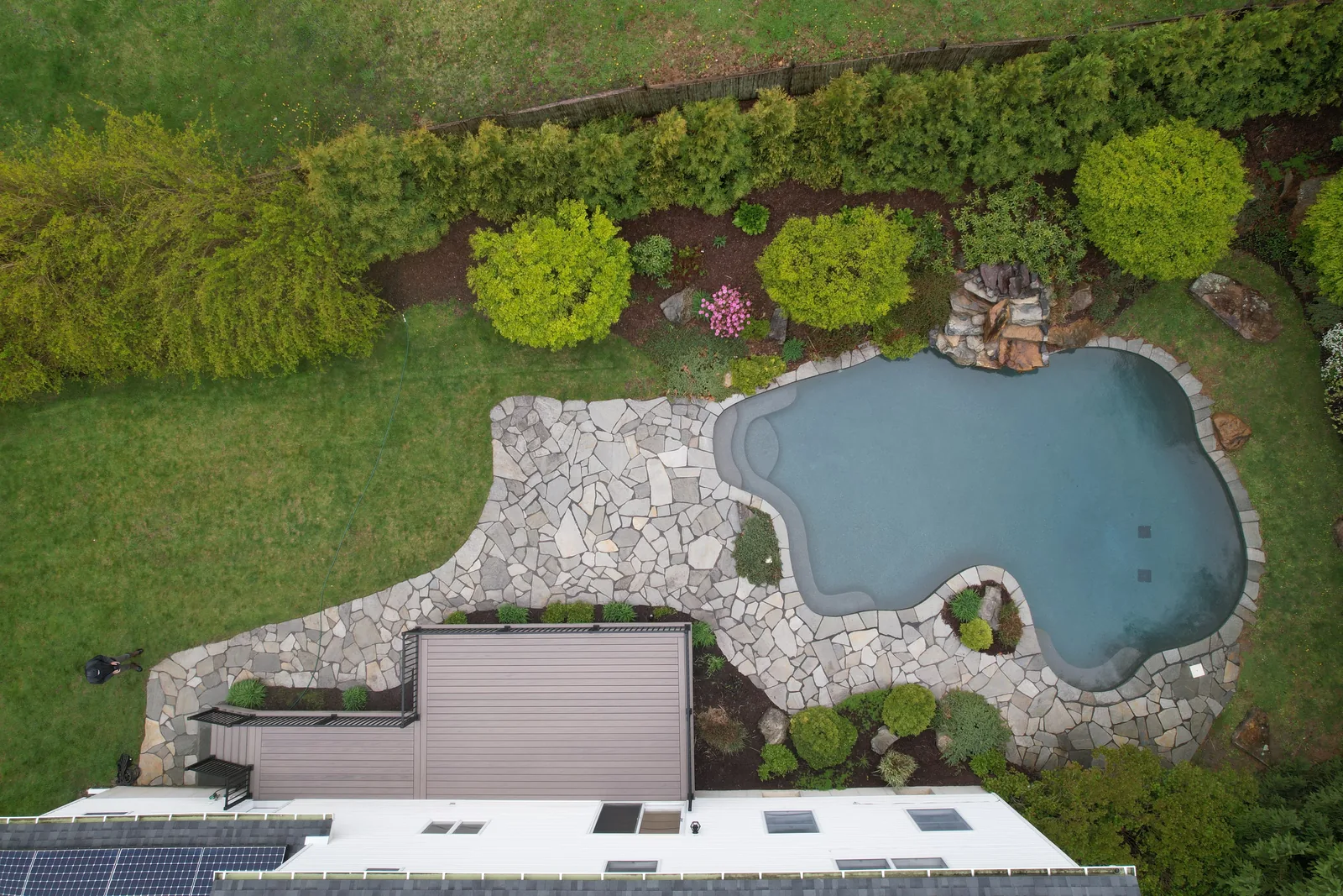 Aerial of a natural pond, waterfall, and flagstone patio beside a deck in the Hudson Valley, NY
