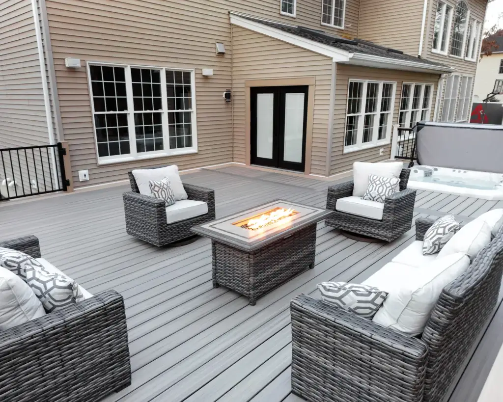 Wide low-profile composite entertaining deck with fire table and lounge seating on a flat Dutchess County lot