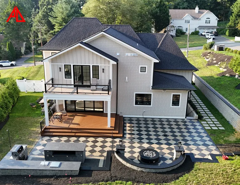 Aerial of a two-level deck over a checkerboard paver patio with a fire pit and outdoor kitchen