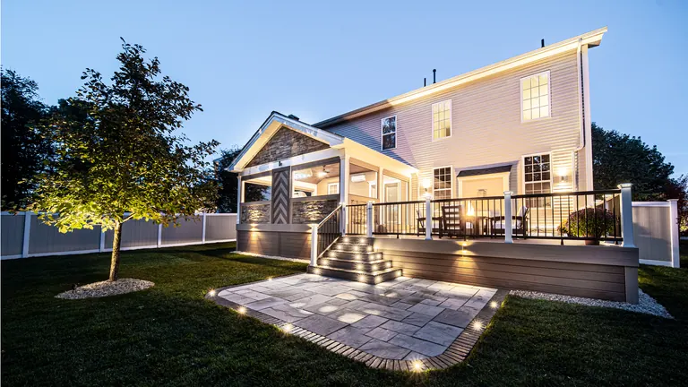 Covered porch and deck at dusk with landscape lighting