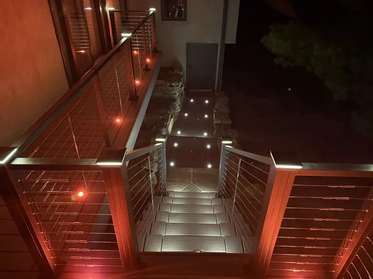 Lit stairs with red-glowing cable railing at night