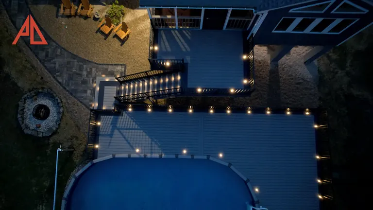 Aerial at night of a lit deck around an above-ground pool