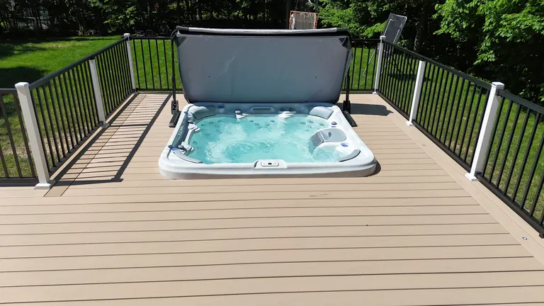 Hot tub set into a deck with black railing