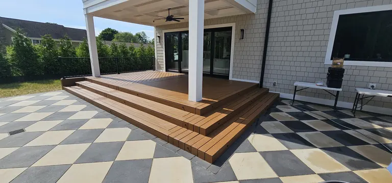 Deck stairs onto a checkerboard patio under a covered porch