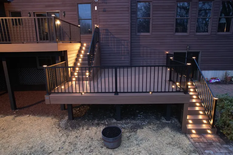 Two-level deck with lit stairs at dusk