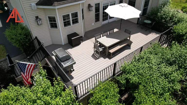 Aerial of a deck with black railing, a grill, and dining under an umbrella
