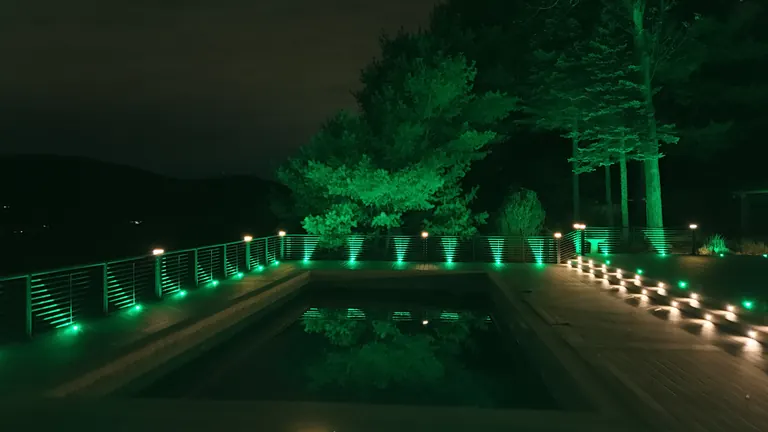 Green rail lights on a deck at night beneath the trees