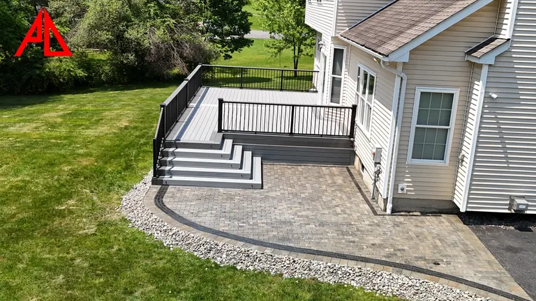 Composite stairs with black railing stepping down to a paver landing