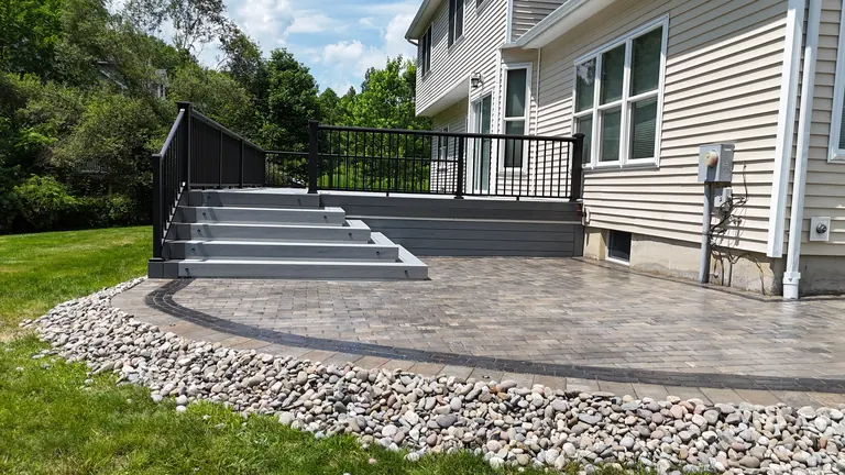 Wide composite stairs down to a stamped patio