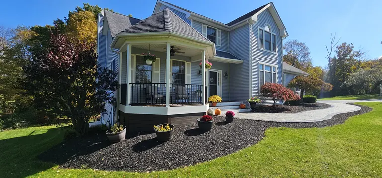 Front porch with black railing and landscaped beds