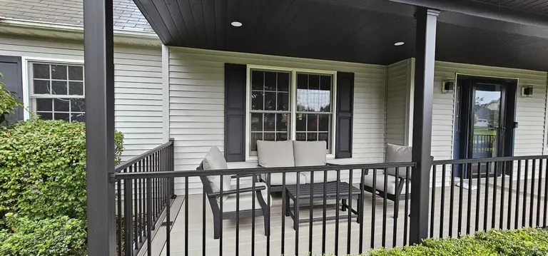 Covered front porch with black railing and lounge seating