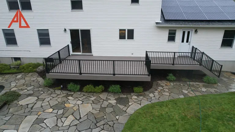 Low deck with black railing above a flagstone patio
