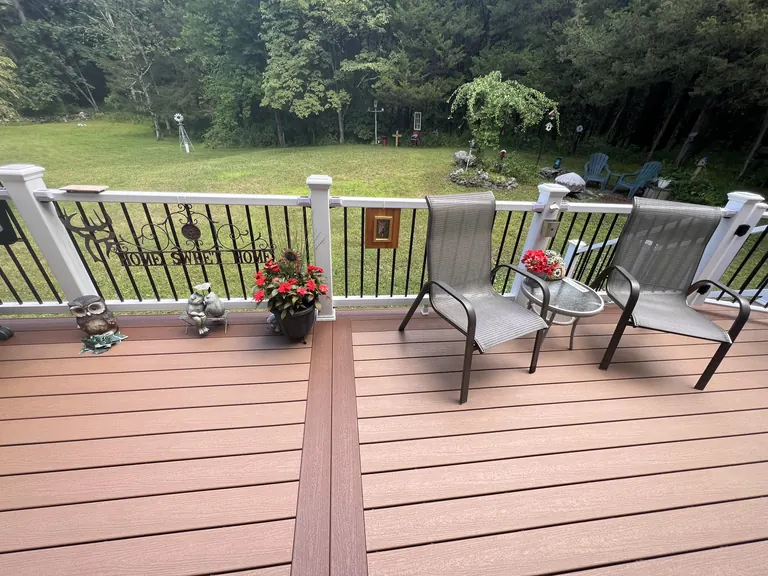 Deck with white railing and patio chairs overlooking a lawn