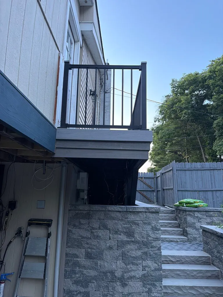 Wide view of a house balcony deck over a stone-clad lower patio and walkway, Rhinebeck, NY