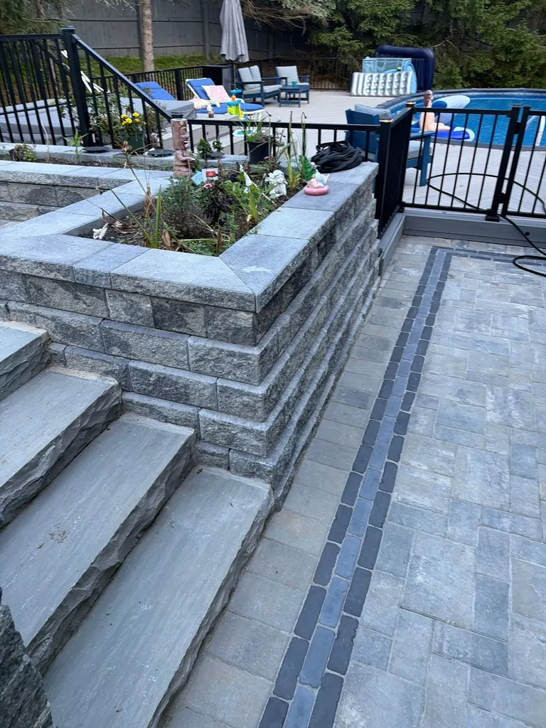 Wide view of stone steps and a planter with pool railing in the background, Rhinebeck, NY