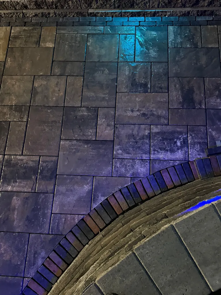 Night shot of a finished herringbone paver patio lit with colorful accent lighting, Boiceville, NY