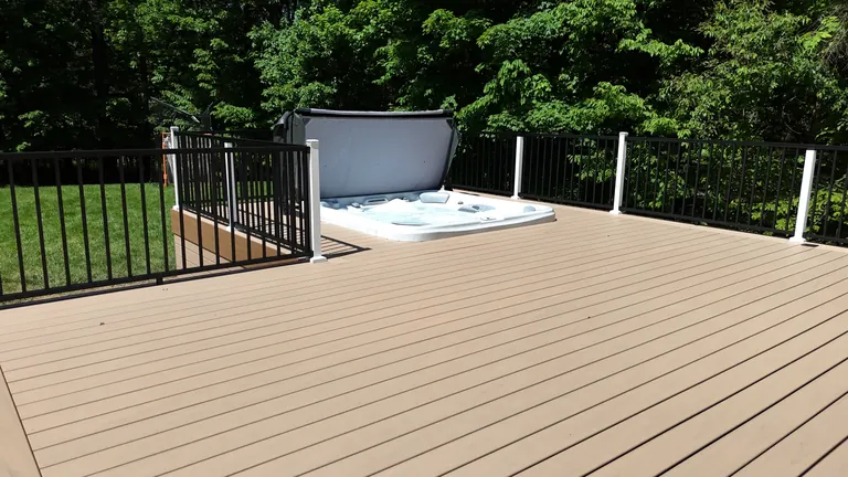Finished composite deck with black aluminum railing and built-in hot tub nook, tree line behind, Lagrangeville, NY