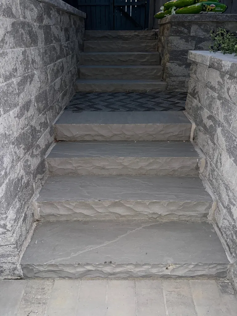 Daytime stacked-stone steps with herringbone paver landing between two retaining walls, Rhinebeck, NY