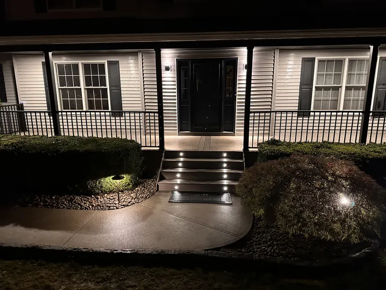 Front porch at night with lit steps and landscape lighting