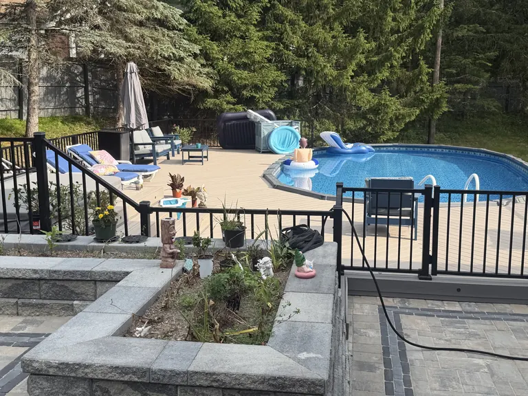 Above-ground pool deck with black aluminum fencing, lounge furniture and umbrella